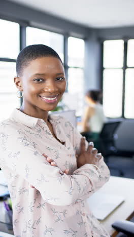 Vertical-video-of-smiling-african-american-businesswoman-in-office,-slow-motion,-copy-space