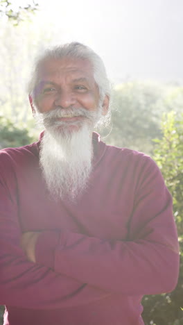 Retrato-En-Video-Vertical-De-Un-Hombre-Birracial-Feliz-Con-Barba-Blanca-Sonriendo-En-La-Naturaleza-Soleada,-Cámara-Lenta