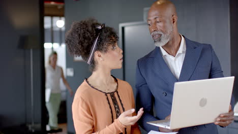 Diverse-business-people-discussing-using-laptop-in-office-with-copy-space