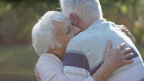 Feliz-Pareja-Caucásica-Mayor-Abrazándose-En-Un-Jardín-Soleado,-Cámara-Lenta