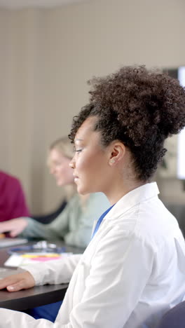 Vertical-video-of-african-american-female-doctor-using-laptop-with-copy-space,-slow-motion