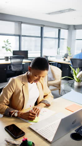 Vertical-video-of-african-american-businesswoman-working-in-office,-slow-motion,-copy-space