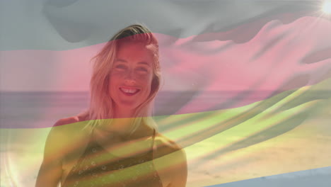 Animación-De-La-Bandera-Ondeante-De-Alemania-Sobre-Una-Mujer-Caucásica-Sonriente-Parada-Contra-El-Mar-En-La-Playa