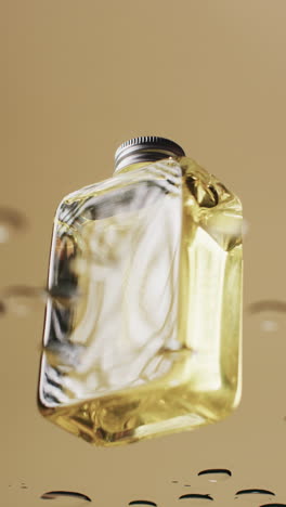 Vertical-video-of-beauty-product-bottle-in-water-with-copy-space-on-yellow-background