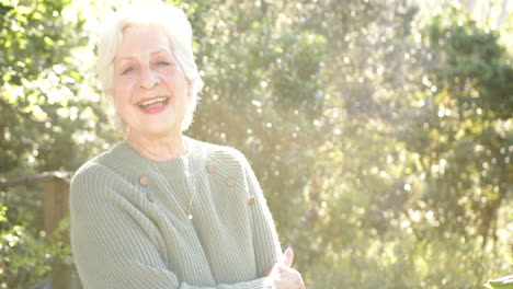 Feliz-Mujer-Caucásica-Mayor-Con-Pelo-Blanco-Sonriendo-En-Un-Jardín-Soleado,-Espacio-Para-Copiar,-Cámara-Lenta