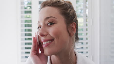 Mujer-Birracial-Feliz-Limpiando-La-Cara-Usando-Algodón-En-El-Baño,-Cámara-Lenta