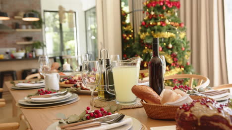 Mesa-De-Comedor-Preparada-Para-La-Comida-De-Celebración-Navideña-Con-árbol-En-El-Fondo,-Cámara-Lenta