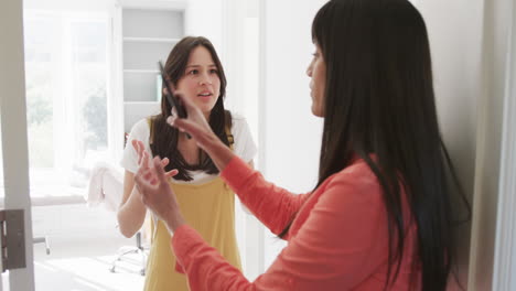 Angry-biracial-mother-and-adult-daughter-with-smartphone-arguing-at-home,-slow-motion