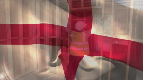 Animation-of-flag-of-england-waving-over-caucasian-male-engineer-wearing-helmet-taking-measurements