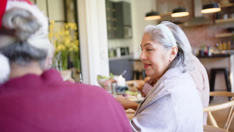 Happy-senior-biracial-woman-at-christmas-dinner-table-with-diverse-friends,-slow-motion