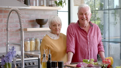 Retrato-De-Una-Feliz-Pareja-Caucásica-Mayor-Cocinando-La-Cena-En-La-Cocina-De-Casa,-Cámara-Lenta