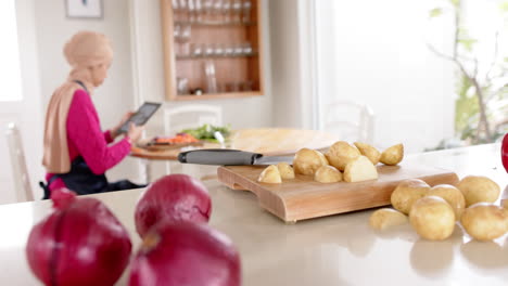 Mujer-Birracial-Con-Hijab-Lavando-Comida-En-La-Mesa-En-Casa-Con-Espacio-Para-Copiar,-Cámara-Lenta