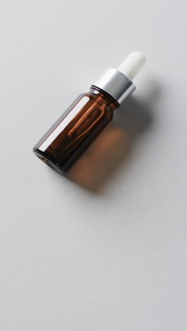 Vertical-video-of-make-up-bottle-with-pipette-and-copy-space-on-white-background