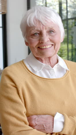 Vertical-video-of-portrait-of-happy-senior-caucasian-woman-smiling-at-home,-slow-motion