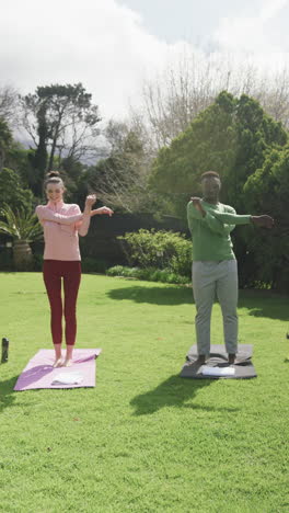 Feliz-Pareja-Diversa-Haciendo-Yoga-En-Un-Jardín-Soleado,-Cámara-Lenta,-Espacio-Para-Copiar