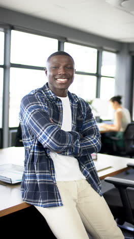 Vertical-video-of-smiling-african-american-businessman-in-office,-slow-motion,-copy-space