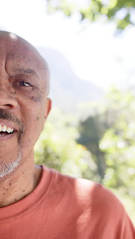 Vertical-video-half-portrait-of-happy-senior-african-american-man-laughing-out-in-sun,-slow-motion