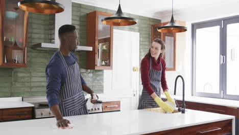 Happy-diverse-couple-washing-dishes-and-cleaning-top-in-kitchen,slow-motion