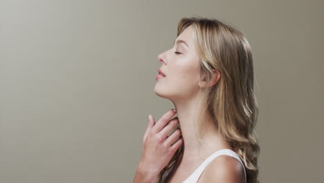 Smiling-caucasian-woman-with-blond-hair-and-make-up-touching-neck,-copy-space,-slow-motion