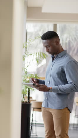 Vertical-video-of-casual-african-american-businessman-using-smartphone,-slow-motion,-copy-space