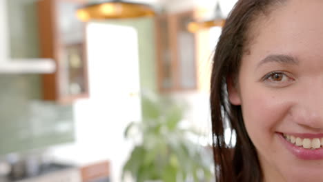 Half-face-of-happy-biracial-woman-with-straight-hair-smiling-in-sunny-kitchen,-copy-space