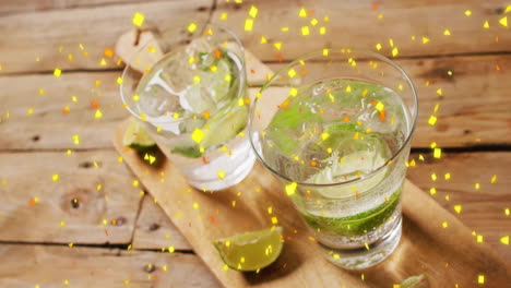 Animation-of-confetti-falling-and-cocktails-on-wooden-background