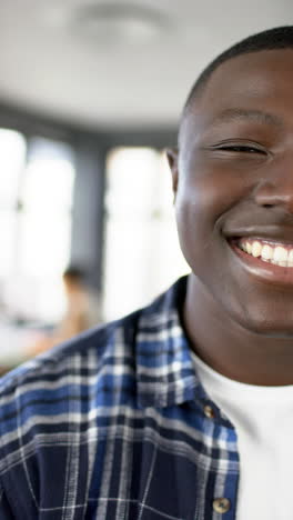 Vertical-video-of-smiling-african-american-businessman-in-office,-slow-motion,-copy-space