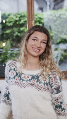 Vertical-video-of-portrait-of-happy-biracial-woman-with-blonde-hair-smiling-at-home,-slow-motion