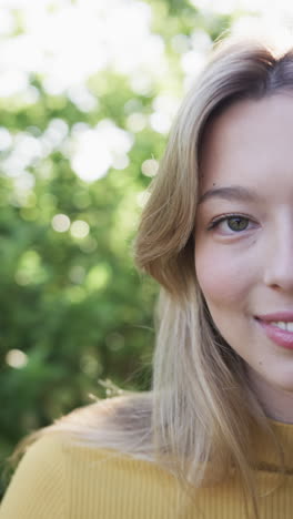 Vertical-video-of-portrait-of-happy-biracial-woman-smiling-in-garden,-slow-motion