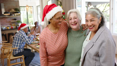 Fröhliche,-Vielfältige-ältere-Freundinnen,-Die-Sich-Nach-Dem-Weihnachtsessen-Mit-Freunden-Umarmen,-Zeitlupe