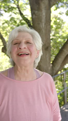 Vertical-video-portrait-of-happy-senior-caucasian-woman-with-white-hair-in-sunny-nature,-slow-motion