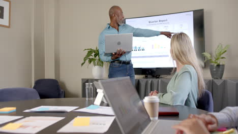 African-american-businessman-using-laptop-giving-presentation-in-office-with-copy-space