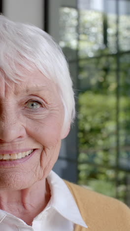 Vídeo-Vertical-De-Retrato-De-Una-Feliz-Mujer-Caucásica-Mayor-Sonriendo-En-Casa,-Cámara-Lenta