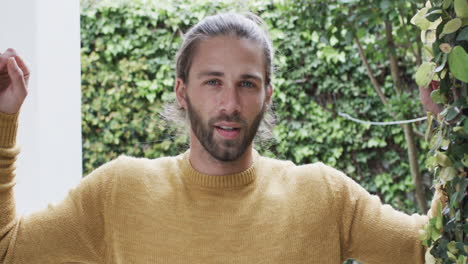 Portrait-of-happy-caucasian-man-wearing-yellow-jumper-in-garden,-slow-motion