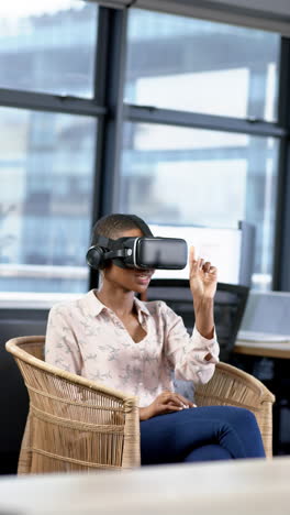 Vertical-video-of-african-american-businesswoman-using-vr-headset-in-office,-slow-motion,-copy-space