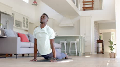 Hombre-Afroamericano-Enfocado-Haciendo-Flexiones-En-Una-Sala-De-Estar-Soleada,-Cámara-Lenta