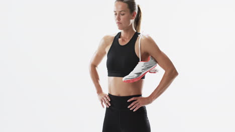 Young-Caucasian-woman-athlete-holds-running-shoes-on-a-white-background