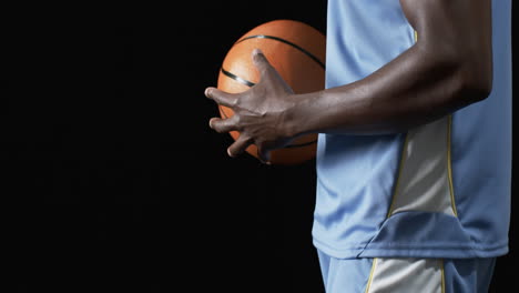 Hombre-Afroamericano-Sosteniendo-Una-Pelota-De-Baloncesto-Sobre-Un-Fondo-Negro