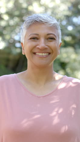 Vertical-video-of-portrait-of-happy-senior-biracial-woman-in-garden,-slow-motion