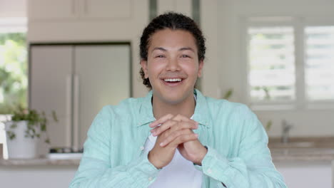 Happy-biracial-man-having-video-call,-talking-and-gesturing-in-kitchen-at-home,-slow-motion