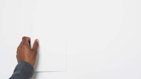 Vídeo-De-La-Mano-De-Un-Hombre-Afroamericano-Sosteniendo-Un-Libro-Con-Páginas-En-Blanco,-Copiando-Espacio-En-Fondo-Blanco