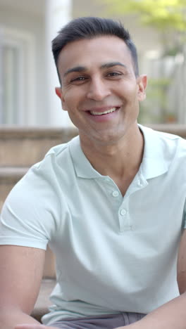 Retrato-En-Video-Vertical-De-Un-Hombre-Birracial-Feliz-Sonriendo-En-Un-Jardín-Soleado,-Cámara-Lenta