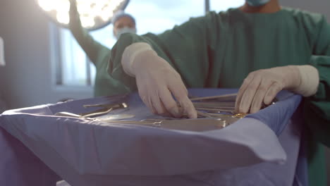 Midsection-of-female-surgeon-preparing-surgical-instruments-in-theatre,-copy-space,-slow-motion