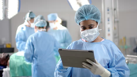 Portrait-of-african-american-female-surgeon-using-tablet-in-operating-theatre,-slow-motion