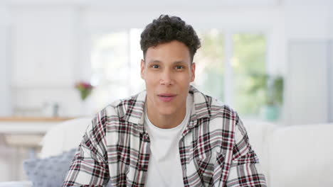 Happy-biracial-man-sitting-on-sofa-having-video-call-at-home,-in-slow-motion