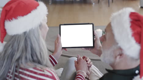 Happy-caucasian-senior-couple-having-christmas-tablet-video-call-with-copy-space,-slow-motion