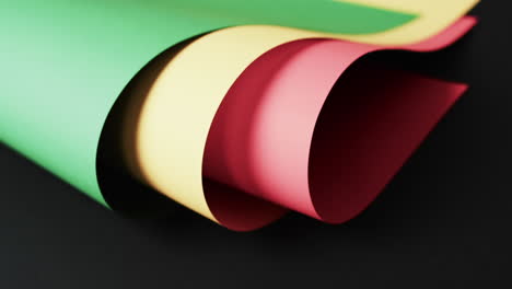 Video-of-rolled-up-red,-yellow-and-green-papers-with-copy-space-on-black-background