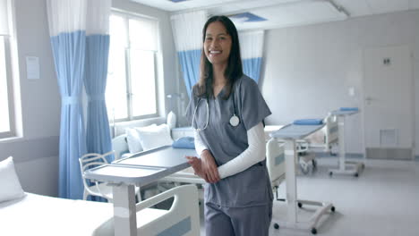 Retrato-De-Una-Feliz-Doctora-Birracial-Vestida-Sonriendo-En-La-Sala-Del-Hospital,-Copiando-Espacio,-Cámara-Lenta