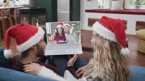 Dos-Parejas-Caucásicas-Felices-Teniendo-Videollamada-Navideña-Con-Computadora-Portátil,-Cámara-Lenta