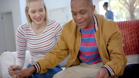 Happy-diverse-group-of-teenage-friends-sitting-on-couch-and-eating-pizza-at-home,-slow-motion